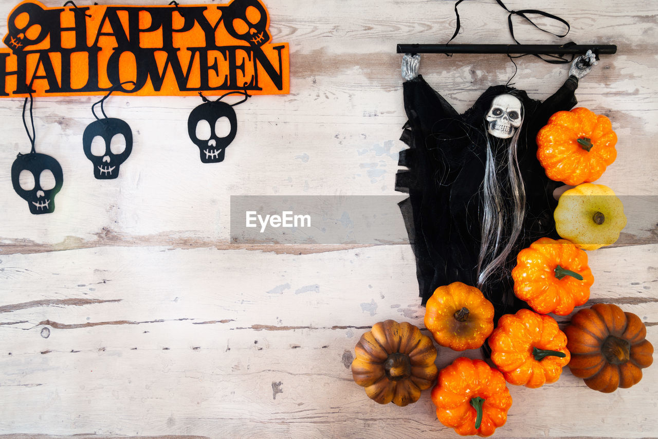 Directly above view of pumpkins and witch against wooden table