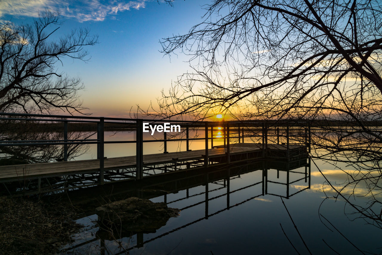 Silhouette bridge over river against sky during sunset