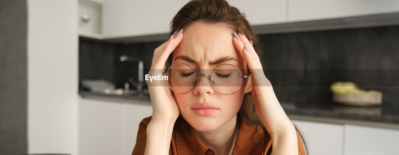 portrait of young woman wearing eyeglasses at home