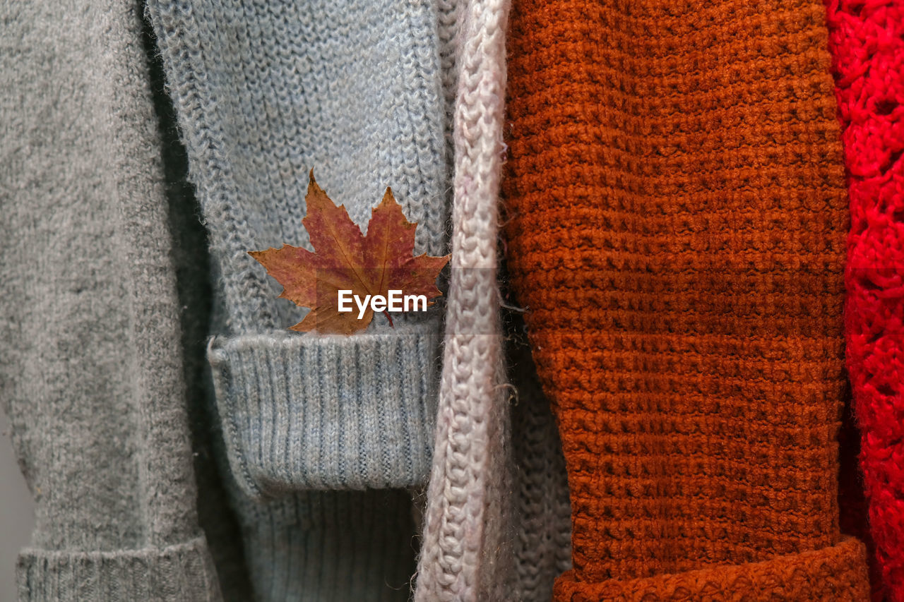Stack of cozy knitted warm sweater with autumn fall maple leaf. sweaters in retro style. orange 