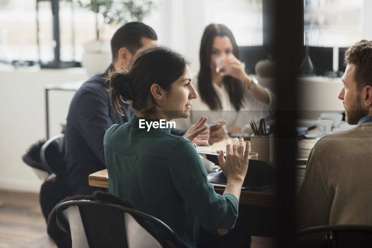 Businesswoman discussing with colleagues during meeting in office