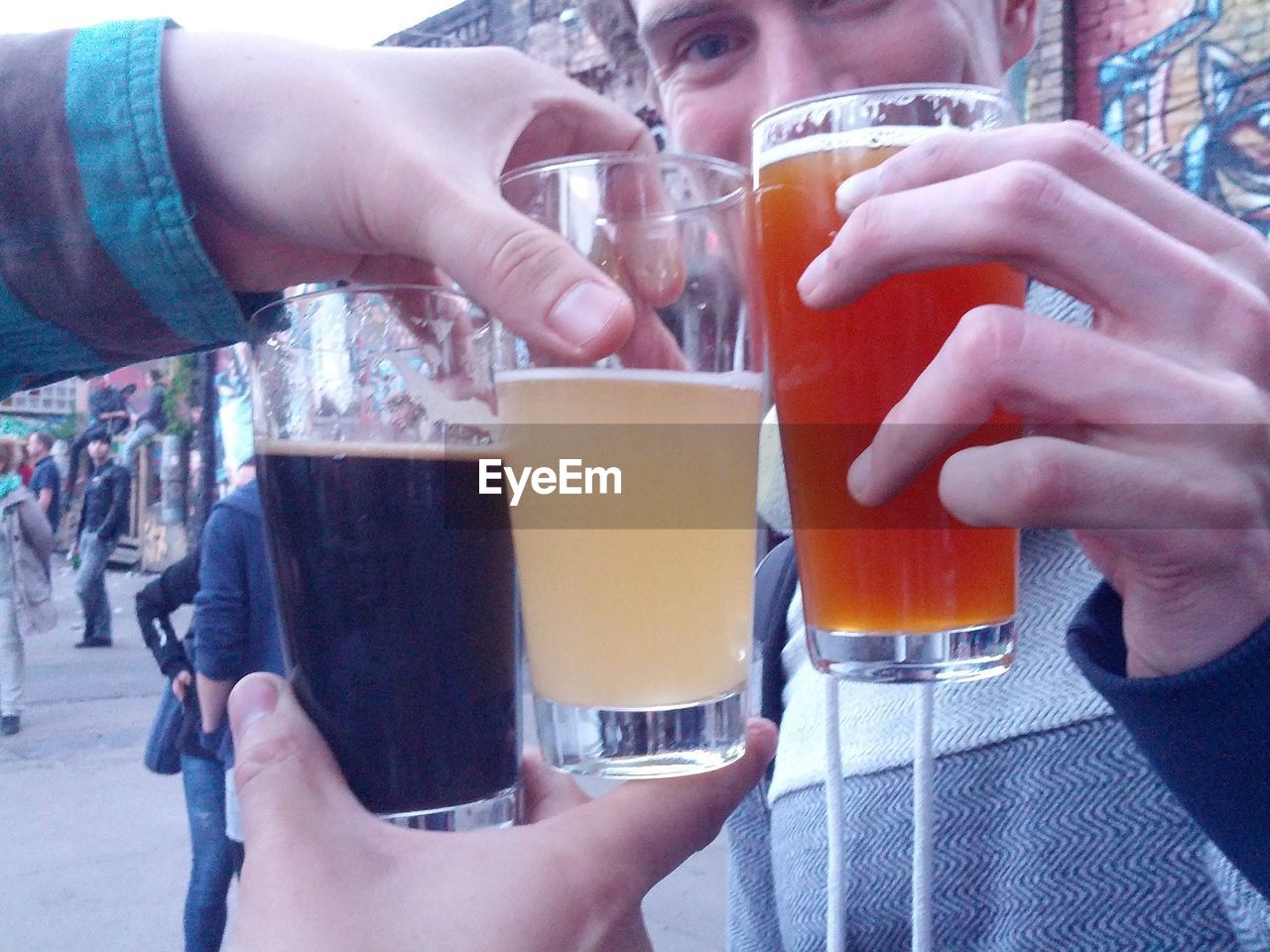Close-up of hands holding drink glasses outdoors