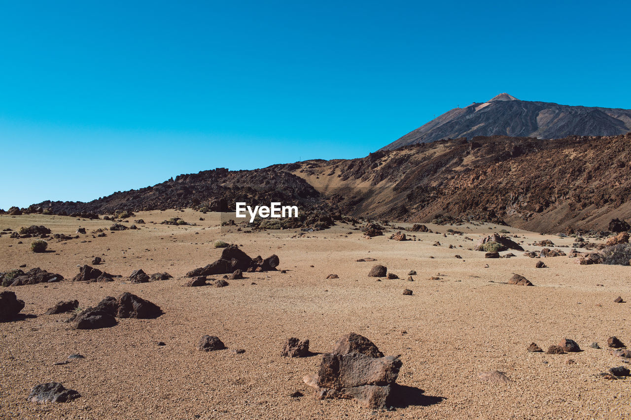 Scenic view of desert against clear blue sky