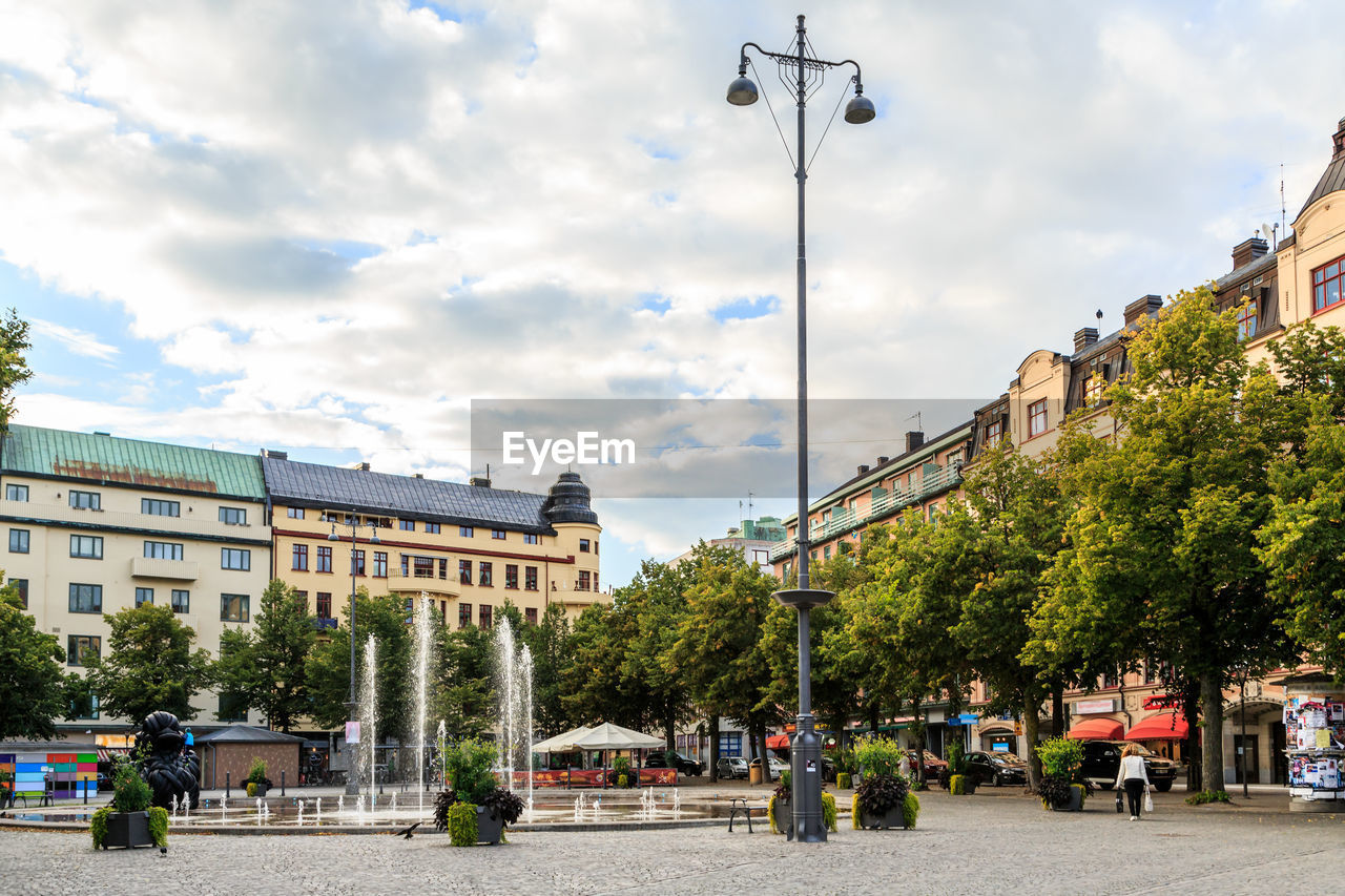 Street by buildings in city against sky