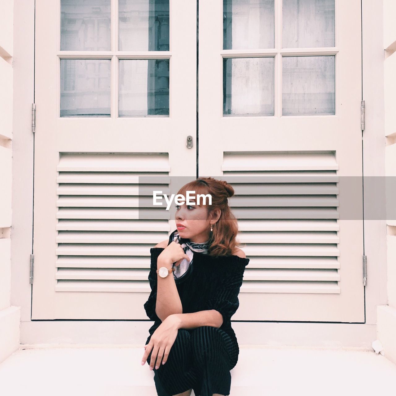 Young woman sitting against door