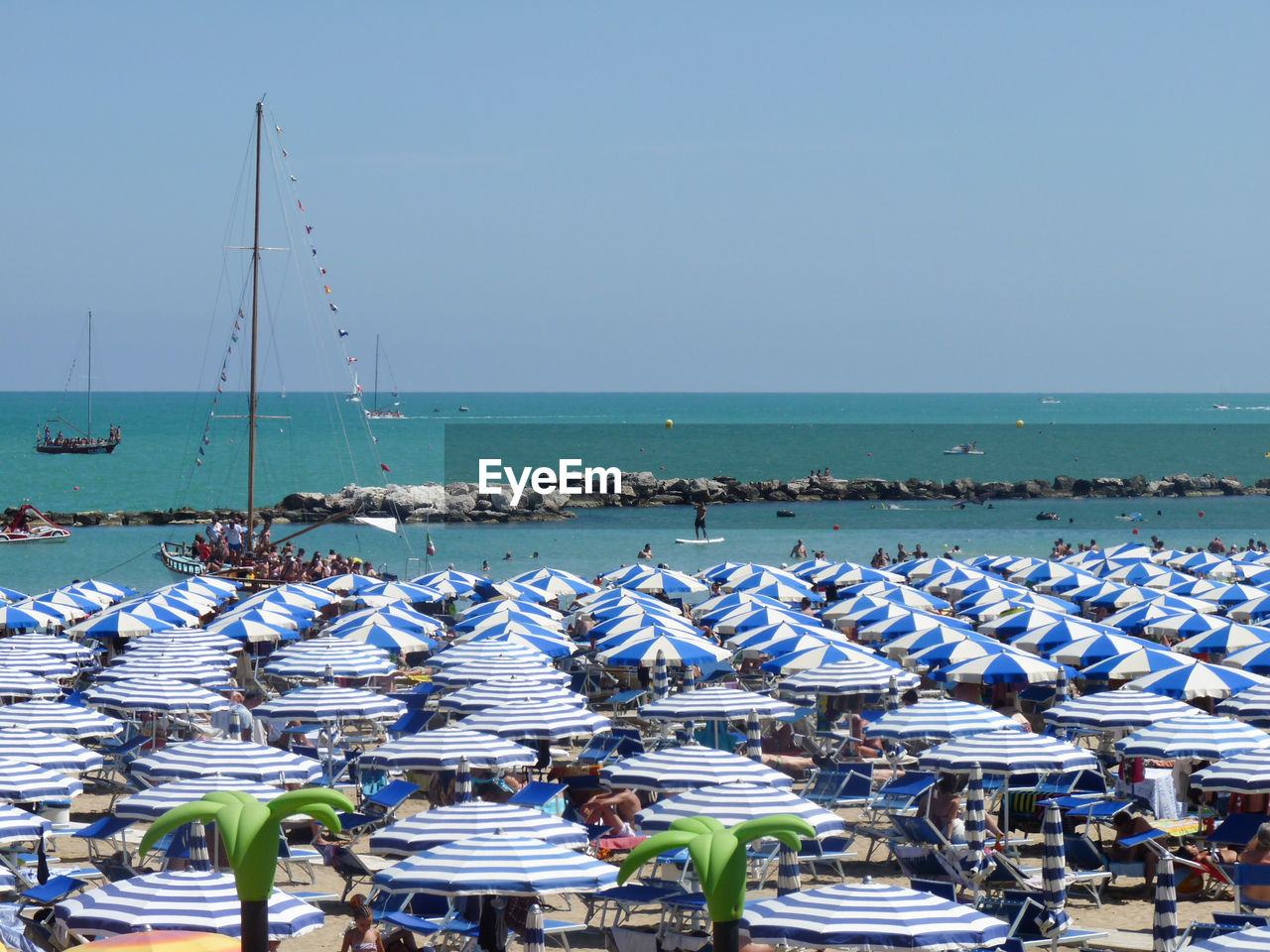 Blue umbrellas at beach against clear sky