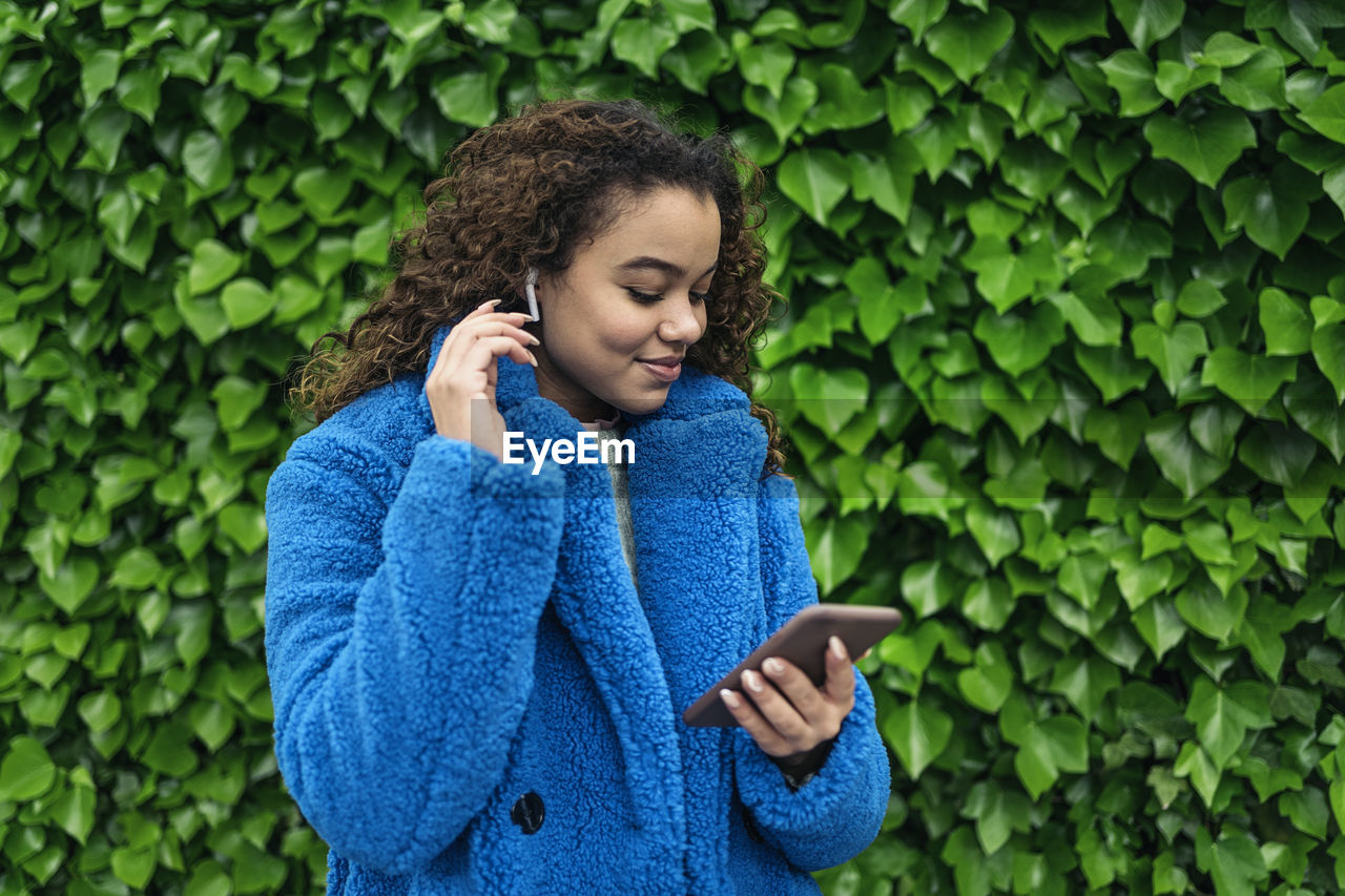 Young woman looking at camera while standing on green mobile phone