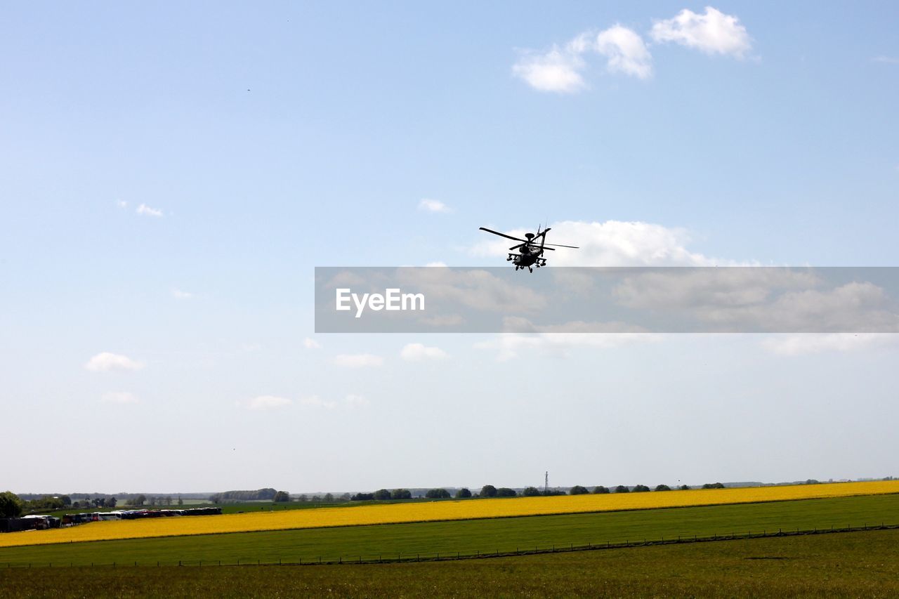 Scenic view of agricultural field against sky with helicopter 