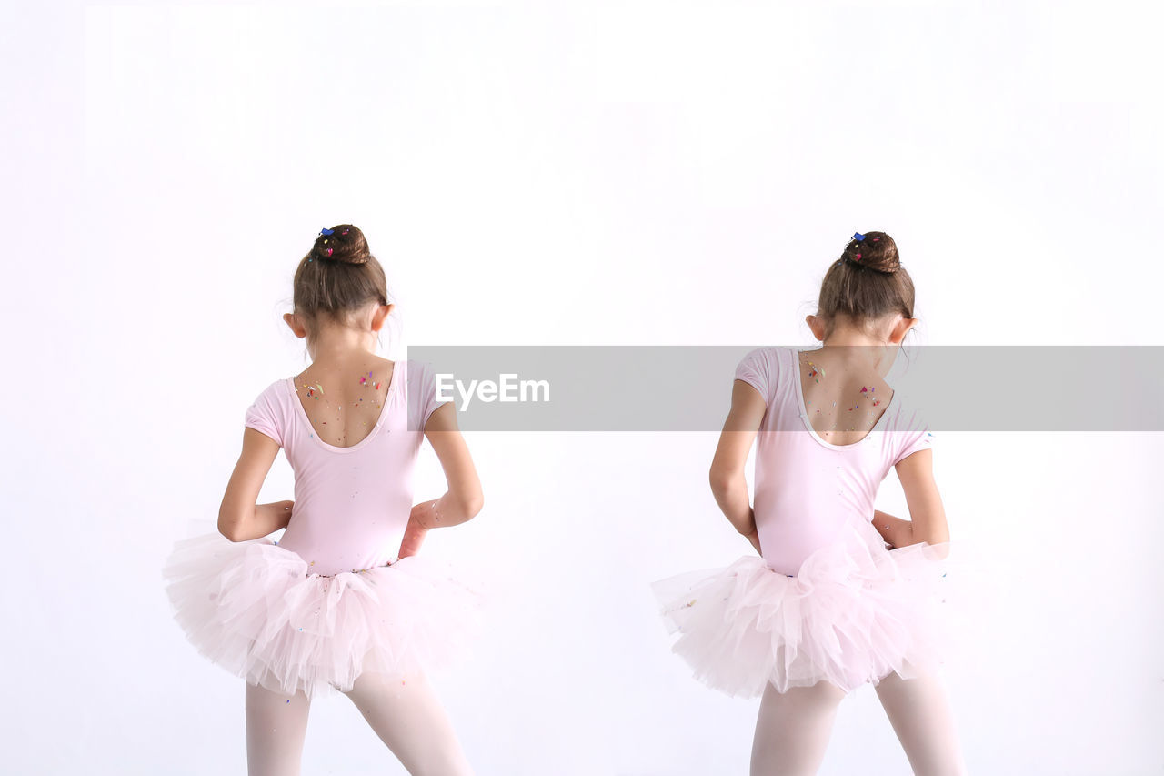 Rear view of girls ballet dancing against white background