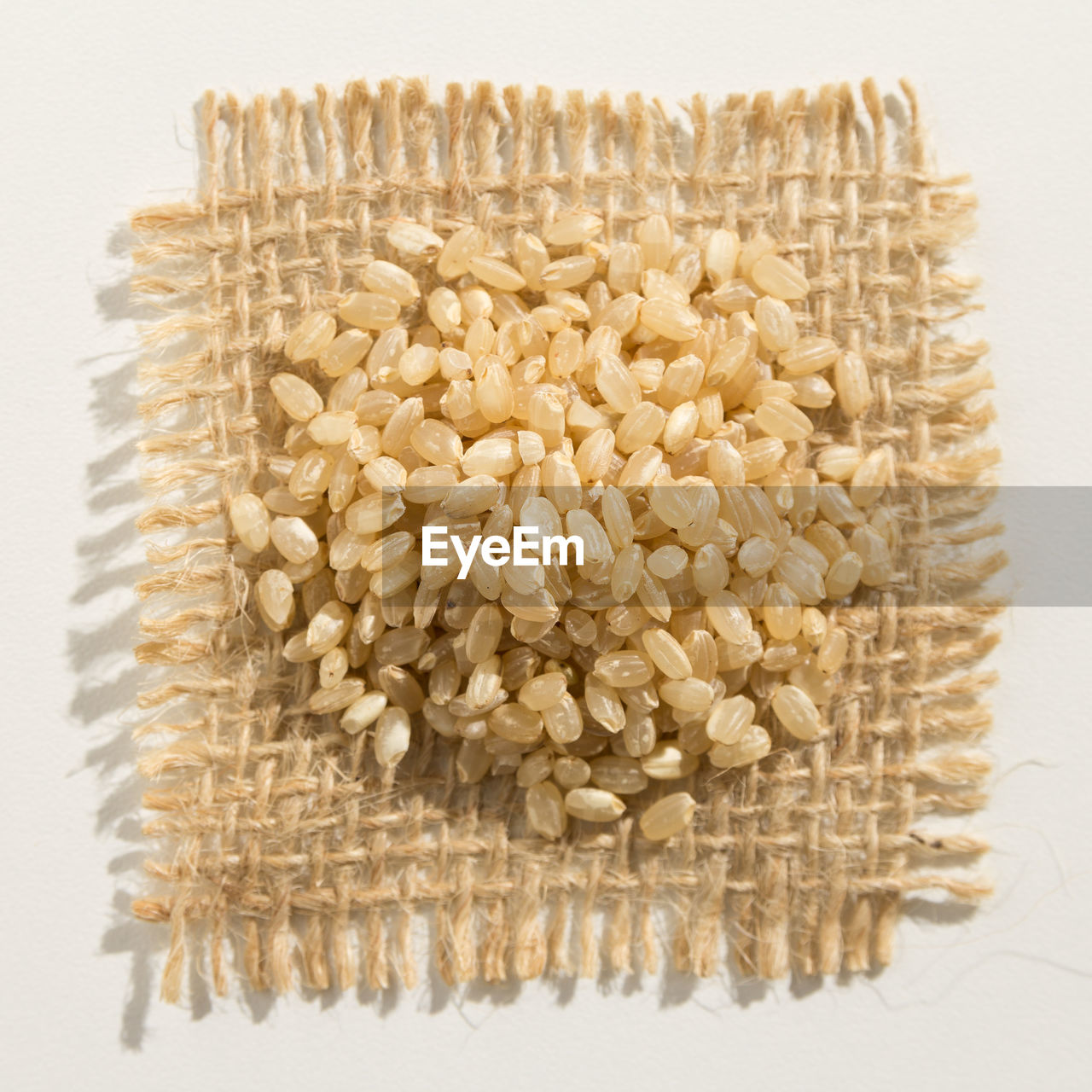 Close-up of rice on jute over white background