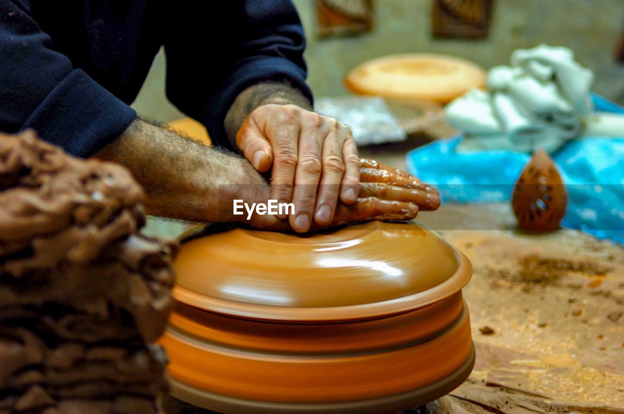 Midsection of potter working at pottery workshop