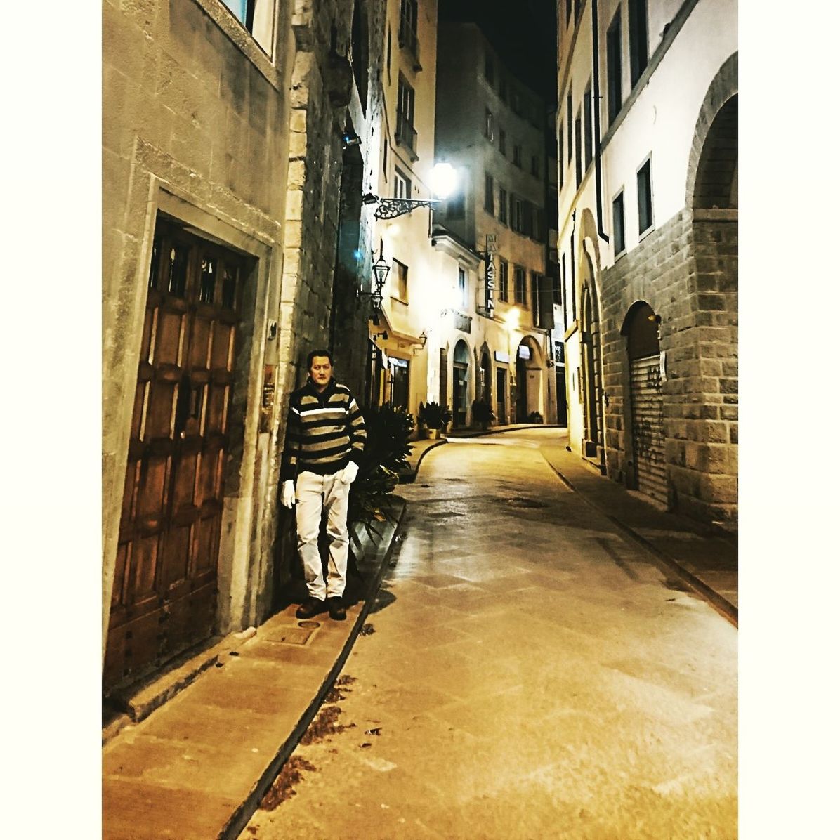 STREET AMIDST ILLUMINATED BUILDINGS AT NIGHT