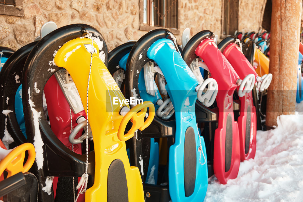 Row of colorful sleds to rent at ski resort. snow sleighs. winter leisure activities