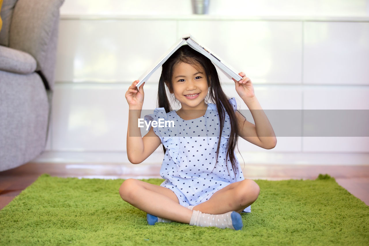 Portrait of smiling girl sitting with book