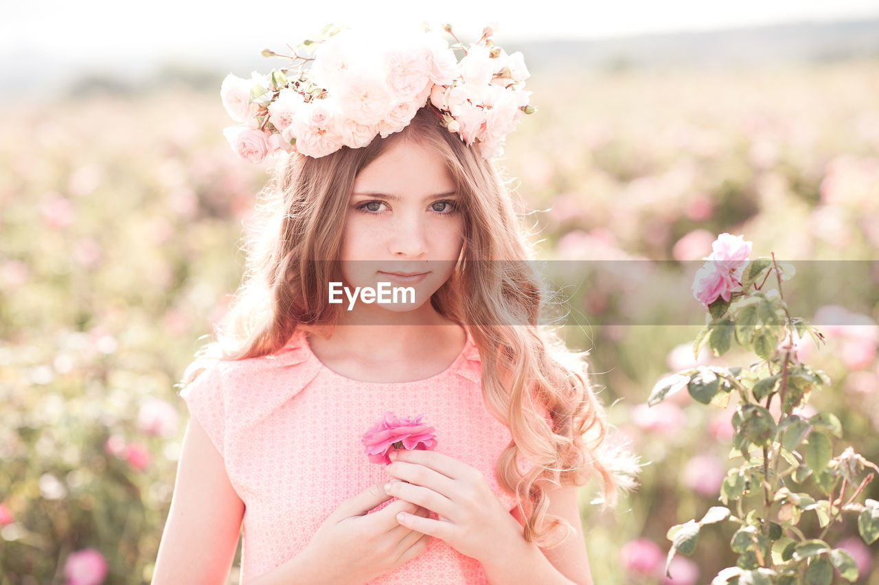 pink, flower, flowering plant, plant, women, portrait, nature, one person, beauty in nature, adult, young adult, hairstyle, long hair, freshness, summer, smiling, child, looking at camera, female, spring, happiness, emotion, fashion, portrait photography, clothing, dress, springtime, blossom, childhood, outdoors, landscape, sunlight, rural scene, wreath, lifestyles, field, looking, relaxation, sky, positive emotion, copy space, laurel wreath, grass, person, environment, front view, meadow, flower arrangement, standing, cute, photo shoot, contemplation, teenager, bride, waist up, pastel colored, day, wildflower, plain, brown hair, blond hair, crown, selective focus, tranquility