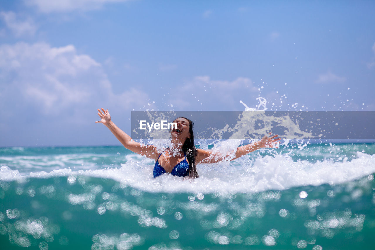 Young woman in sea against sky