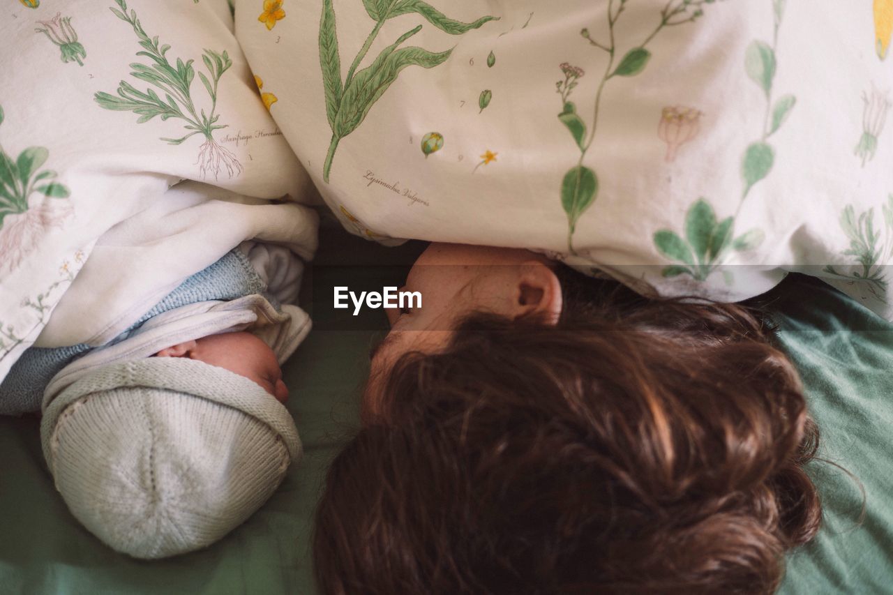 High angle view of mother and son sleeping on bed at home