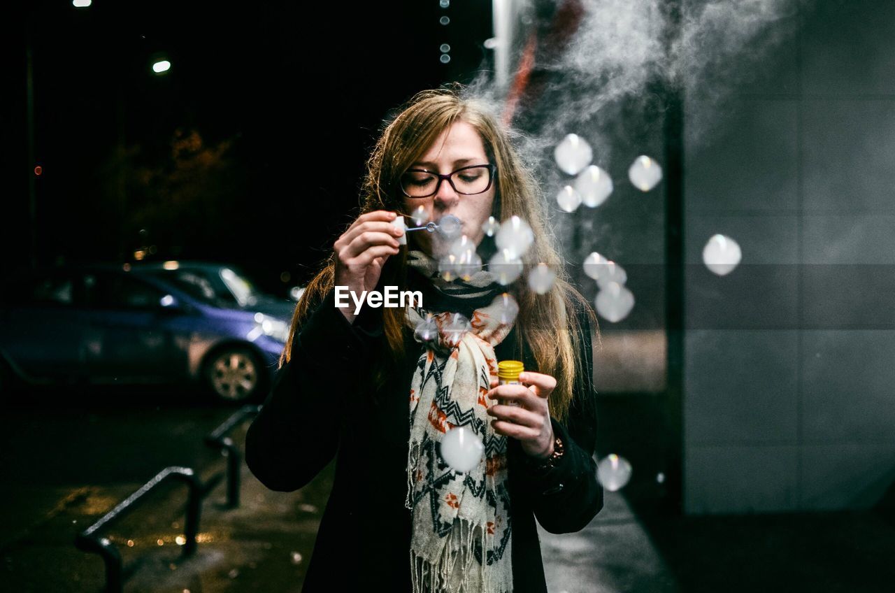 Woman blowing bubbles at night