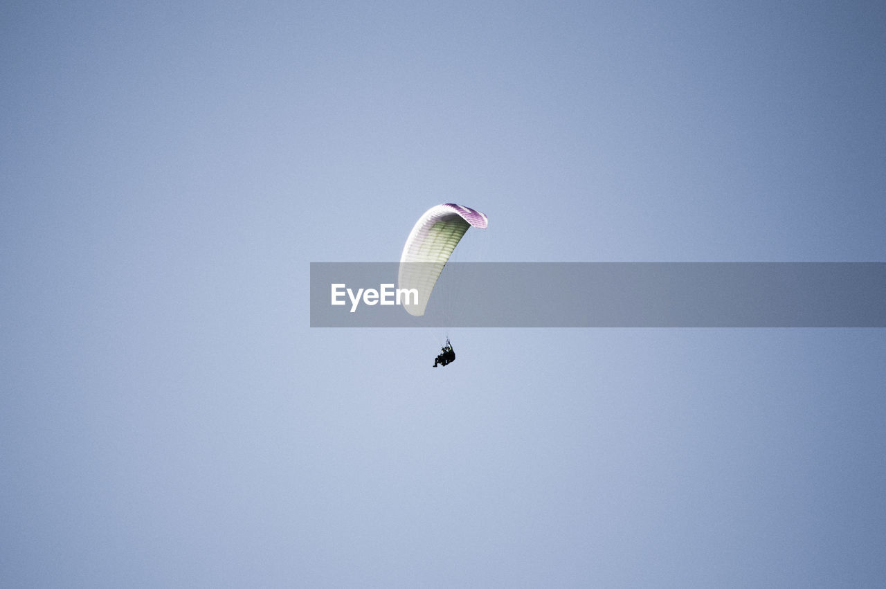 Low angle view of person paragliding in clear sky