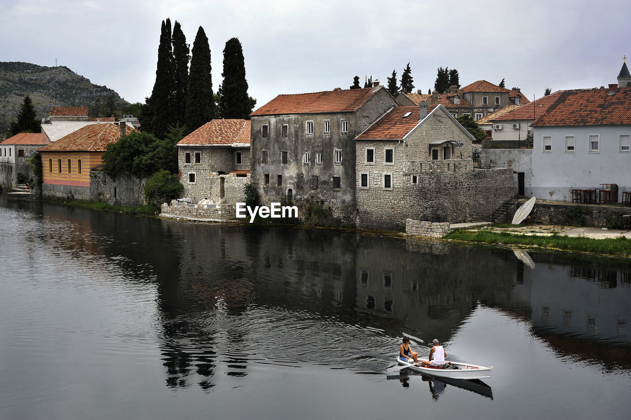 Couple in boat on river by houses