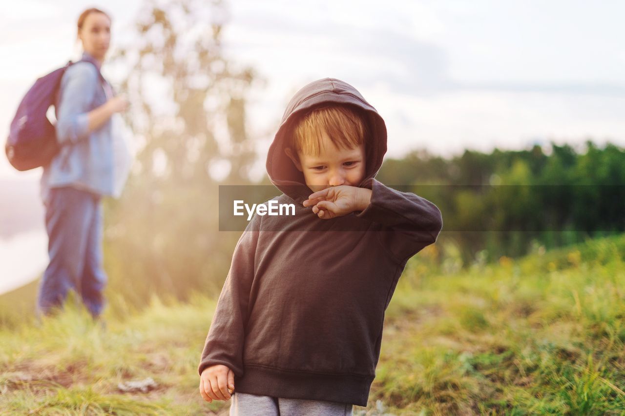 boys, childhood, father, son, family with one child, focus on foreground, family, grass, field, three people, casual clothing, mid adult men, day, outdoors, togetherness, real people, leisure activity, full length, nature, men, bonding, tree, growth, child, food, sky, freshness, close-up, adult, people