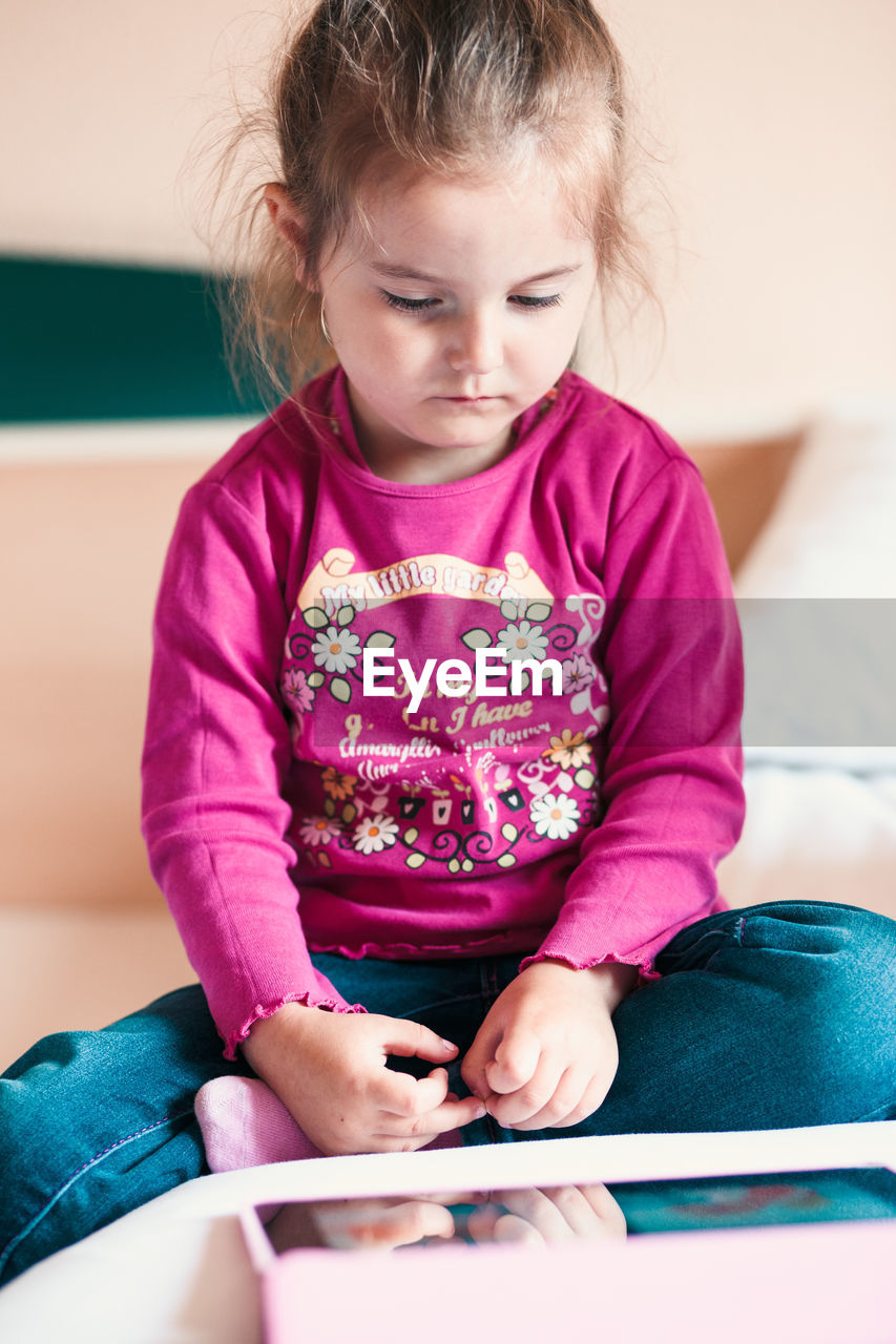 Cute girl watching video in digital tablet at home