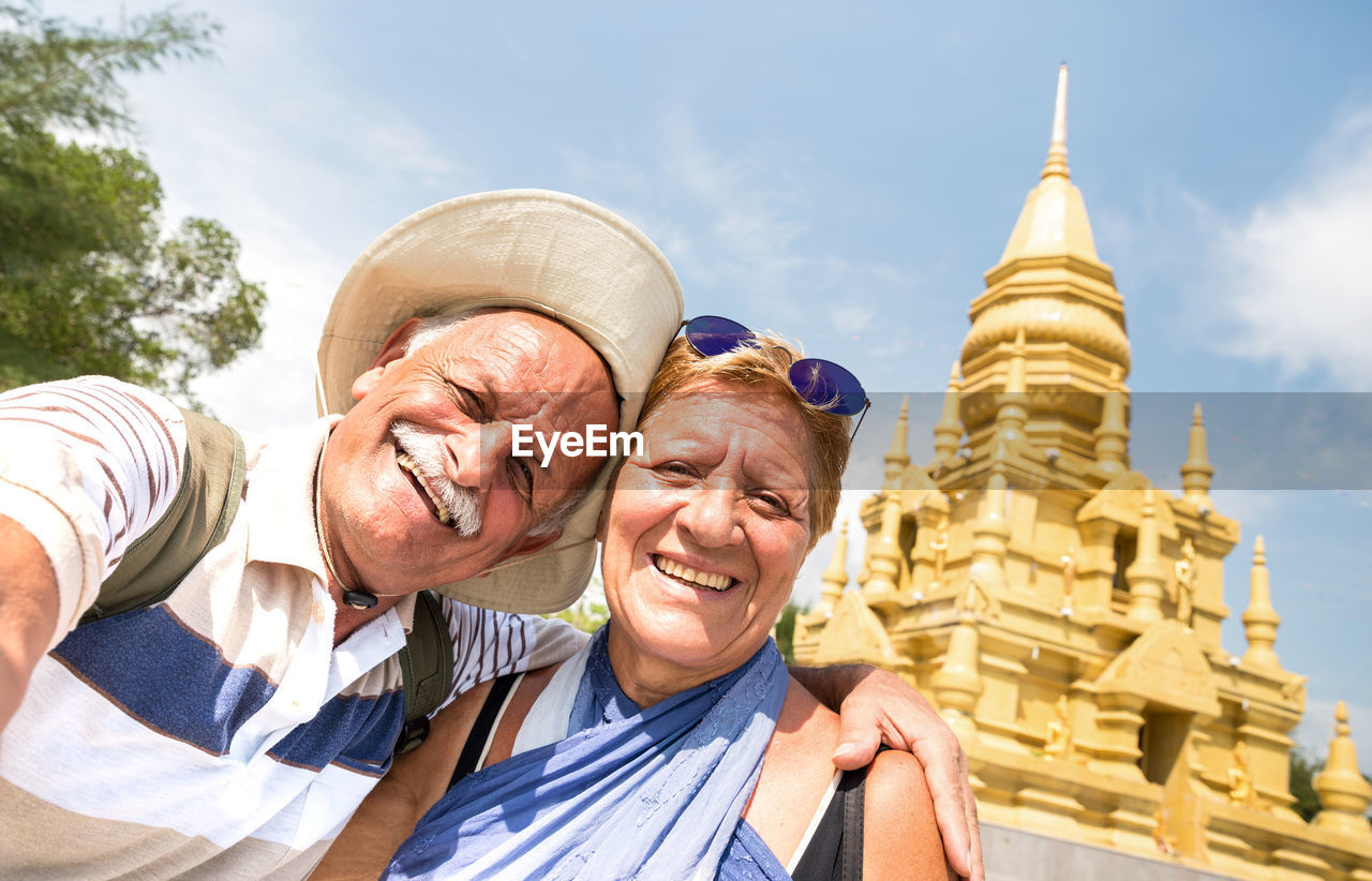 Portrait of smiling couple against temple and sky