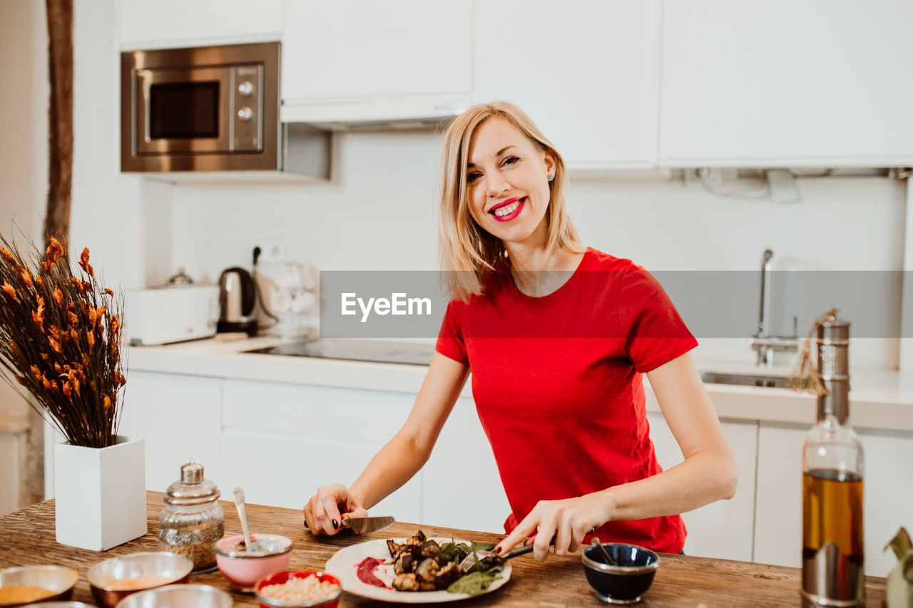 Portrait of smiling woman preparing food in kitchen at home