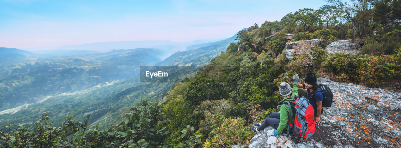 rear view of woman standing on mountain against sky