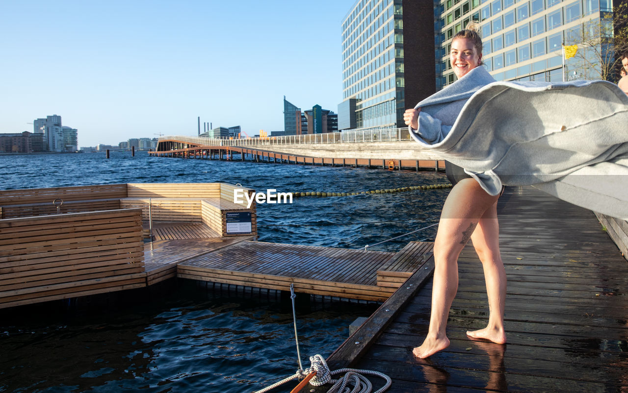 Woman holding robe open on a windy winter day after swim in copenhagen