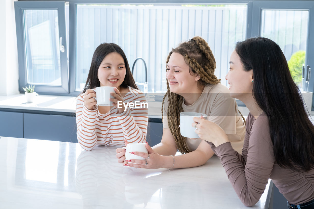 Happy friends with coffee cup sitting at home