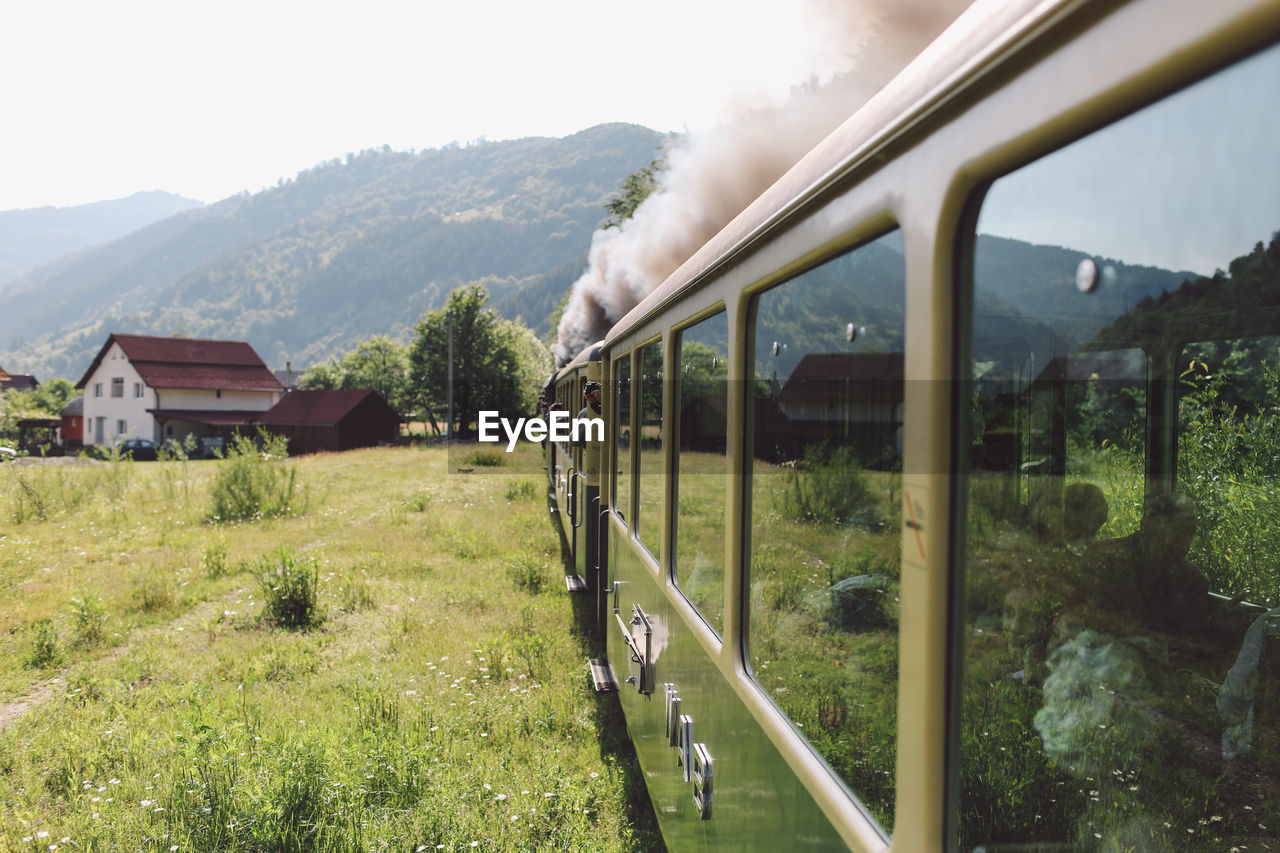 Train moving through landscape with mountain range in background