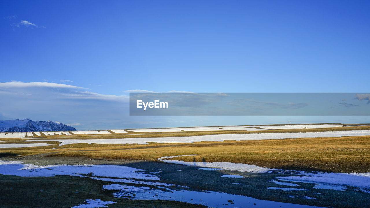 Scenic view of snowcapped mountains against blue sky