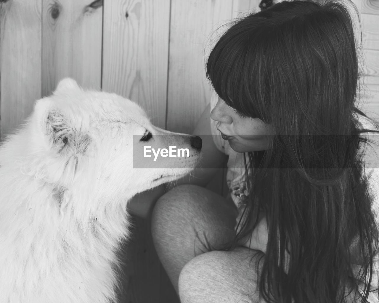 Young woman puckering lips while looking at dog outdoors