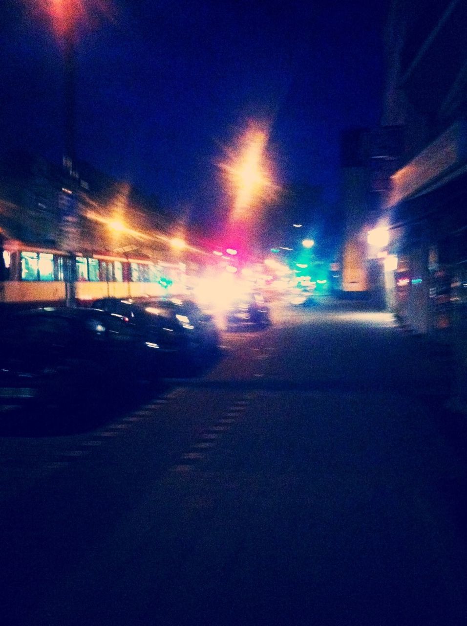 ROAD PASSING THROUGH ILLUMINATED CITY AT NIGHT