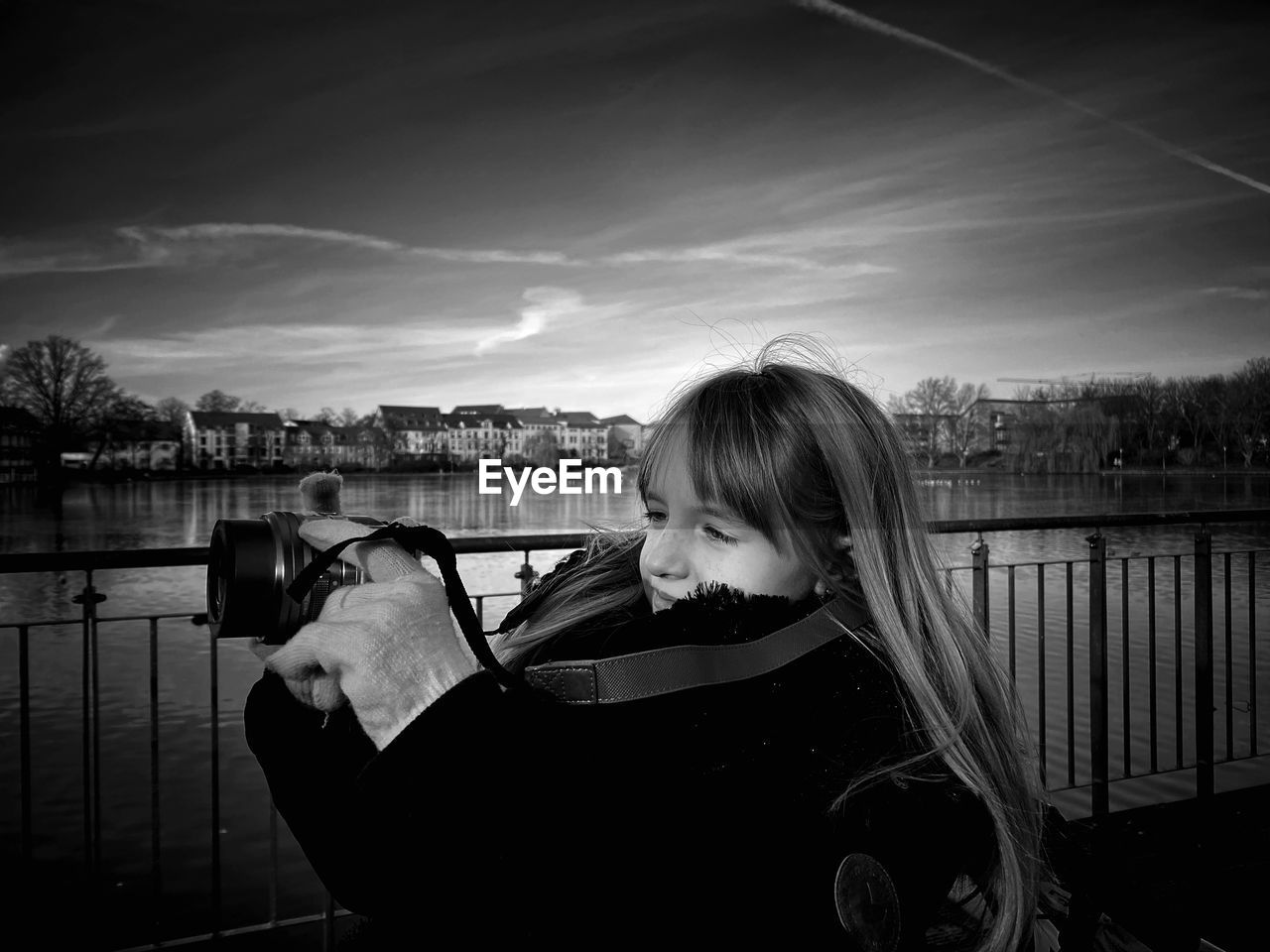 Cute girl photographing while standing by railing