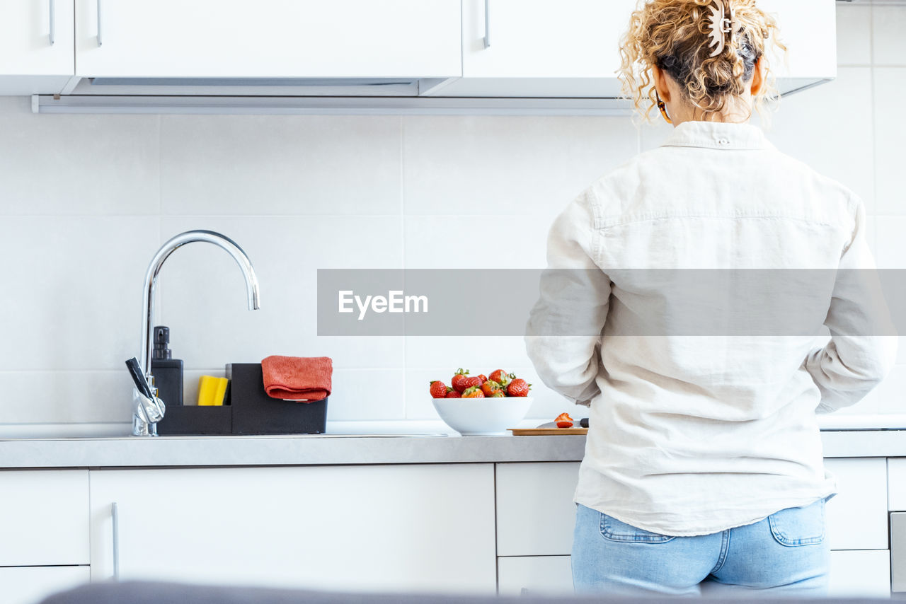 rear view of woman standing in bathroom at home