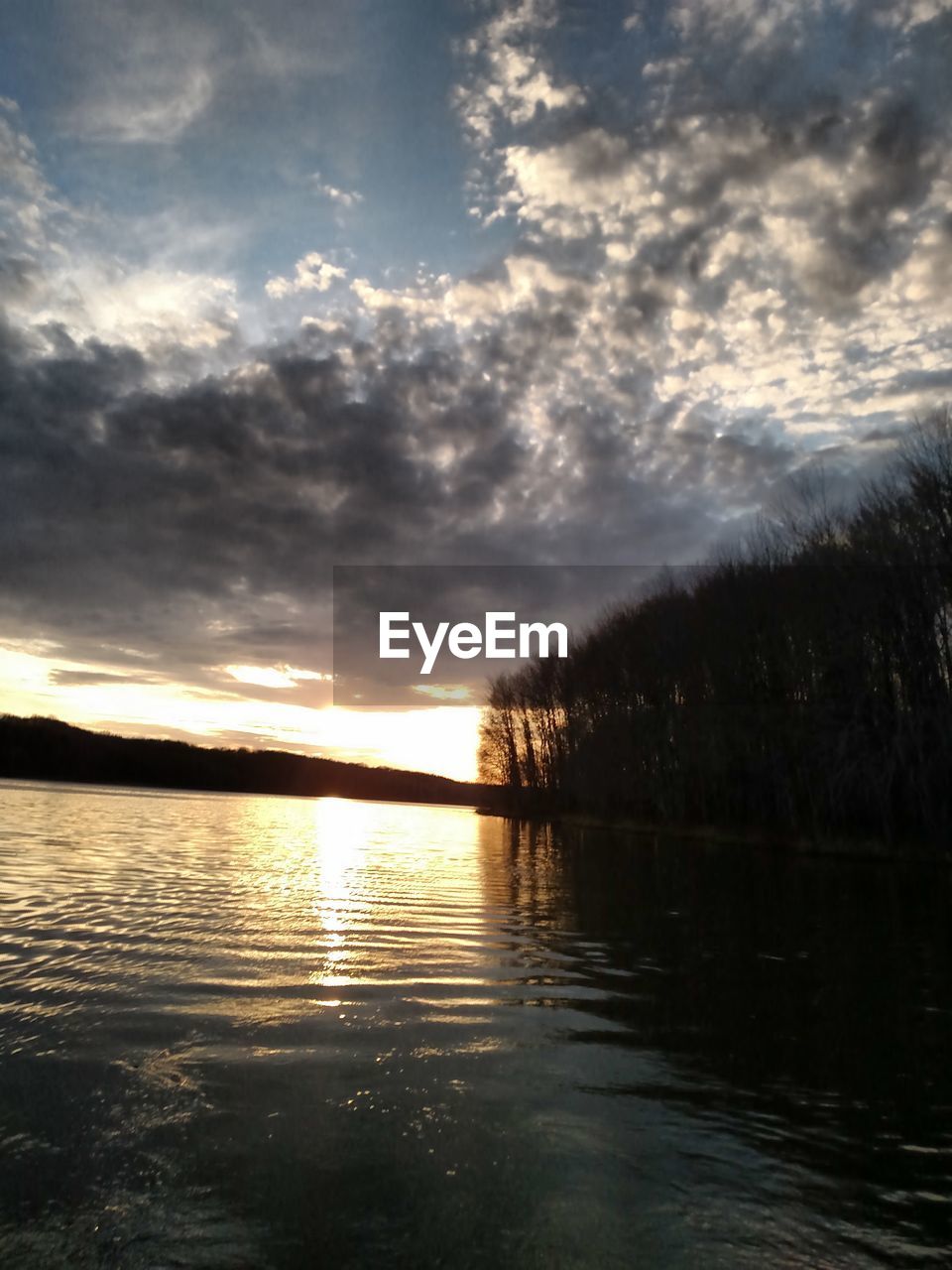 SCENIC VIEW OF LAKE AGAINST CLOUDY SKY AT SUNSET