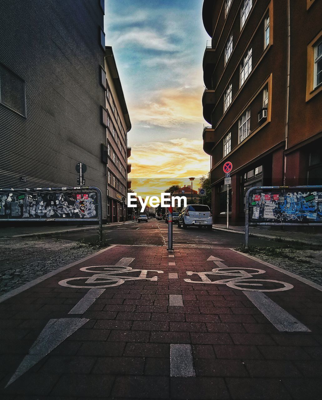 CITY STREET BY BUILDINGS AGAINST SKY DURING SUNSET