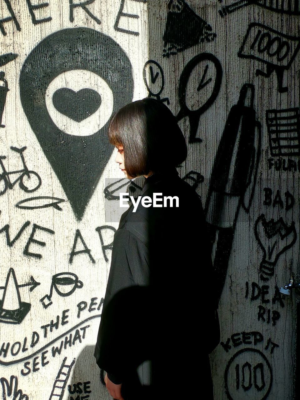 Rear view of woman standing against graffiti wall