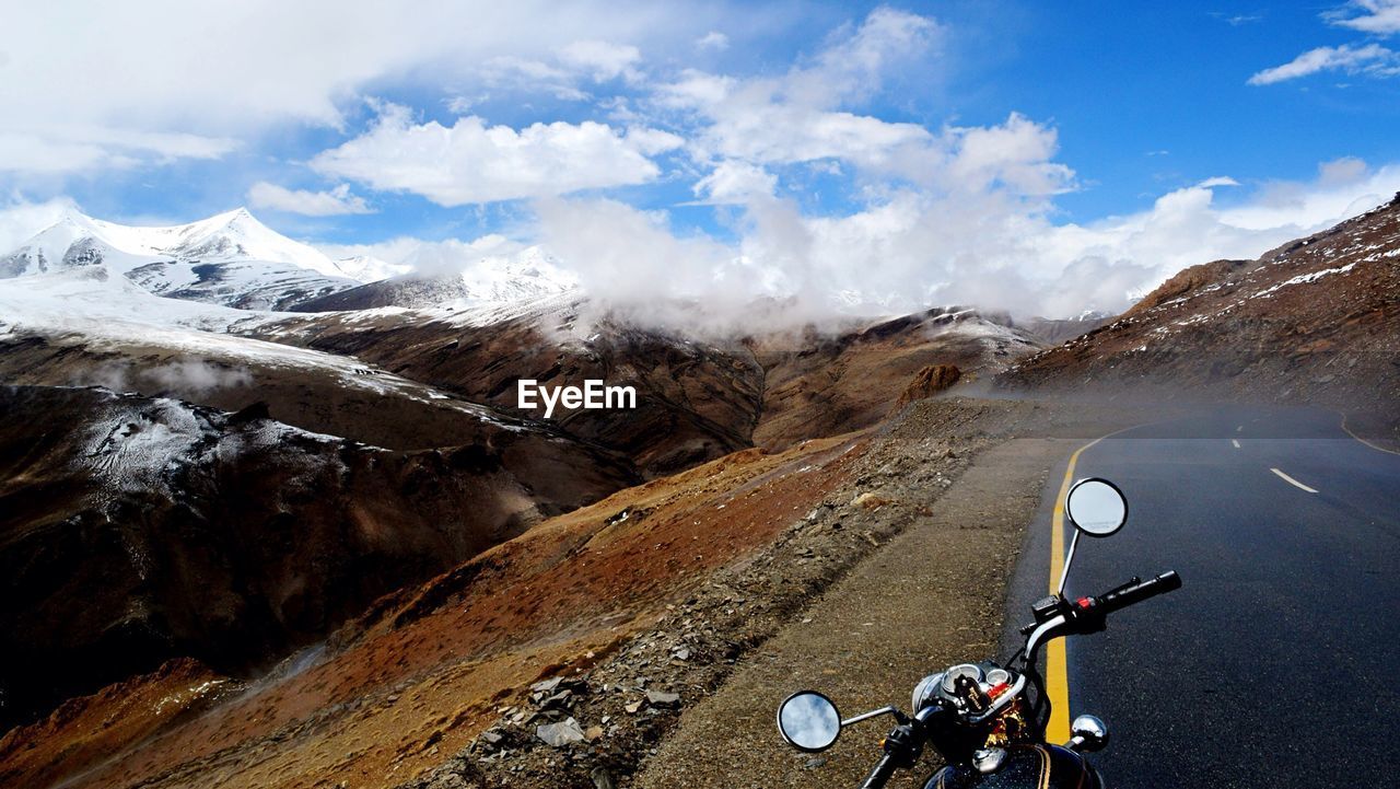 High angle view of motorcycle on street against mountains and cloudy sky
