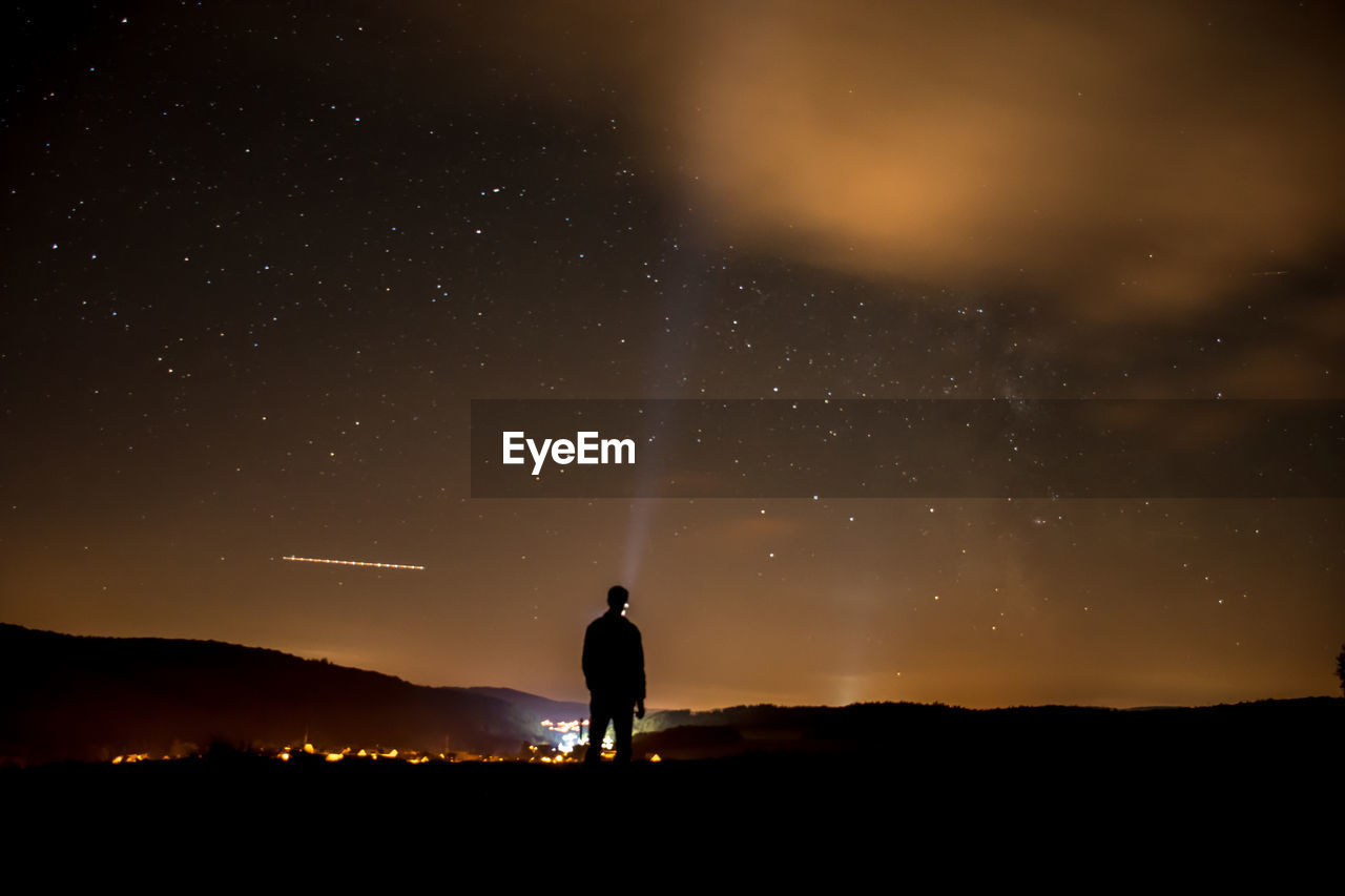 Rear view of man standing on mountain at night