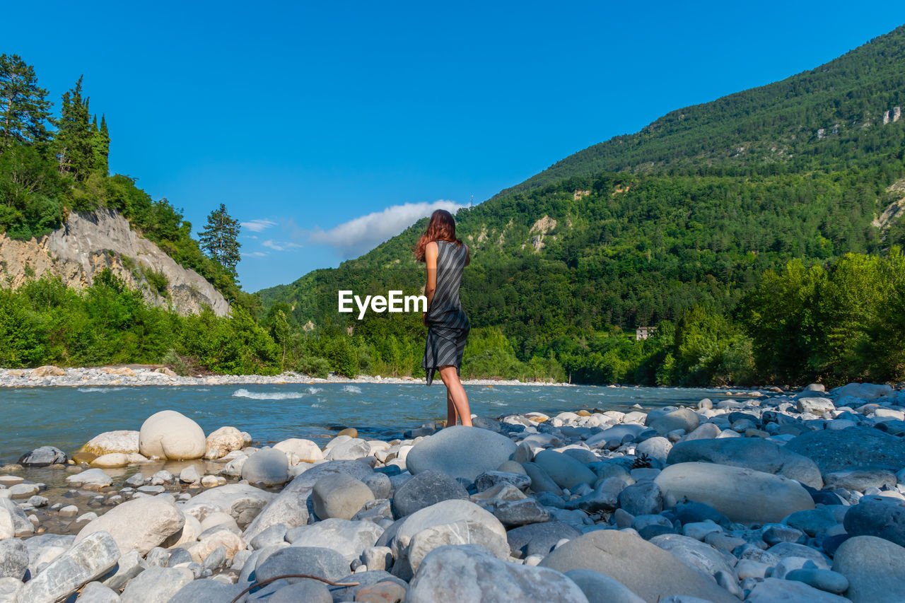 Full length of woman standing by river in forest