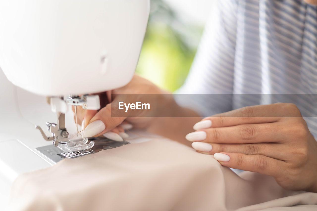 cropped hand of person working on sewing machine