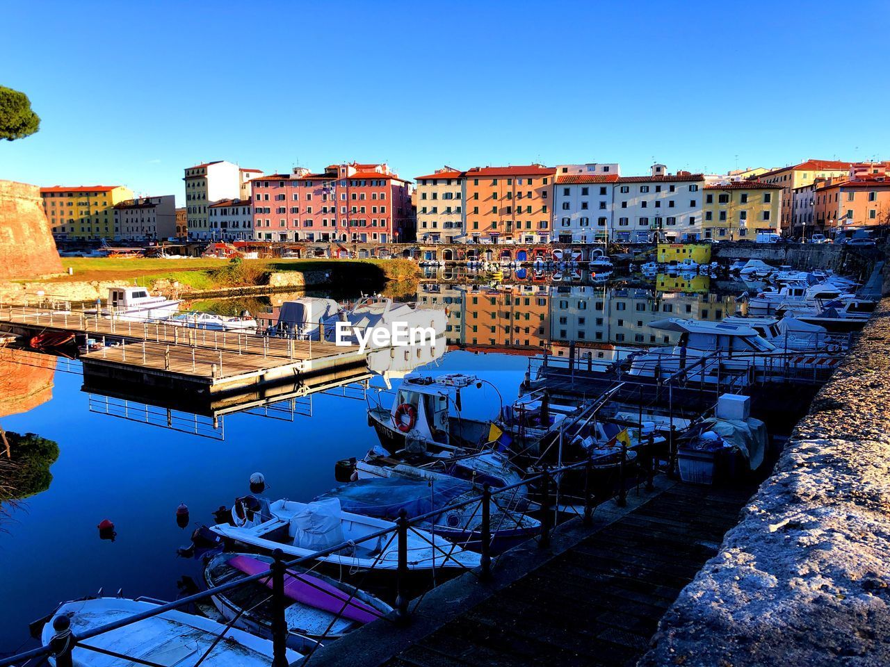 High angle view of buildings by canal against clear blue sky