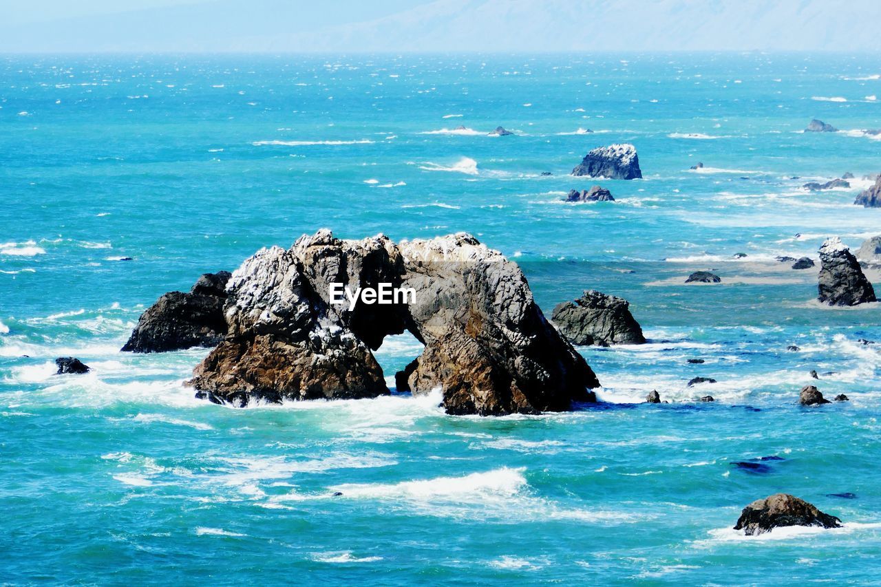 Scenic view of rocks in sea against sky