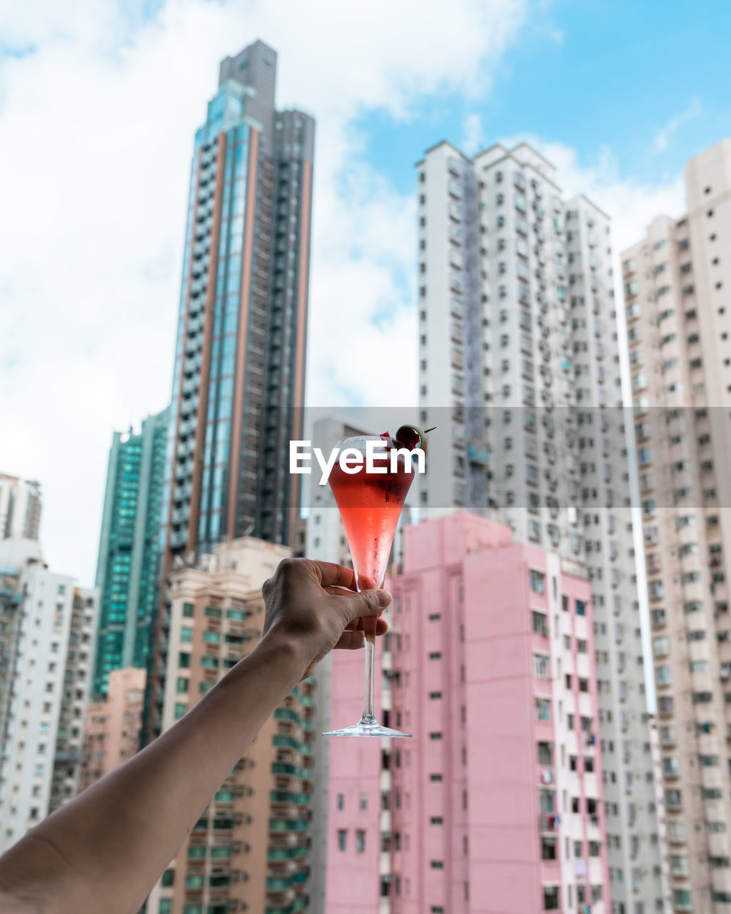 PERSON HOLDING GLASS BUILDING AGAINST SKY