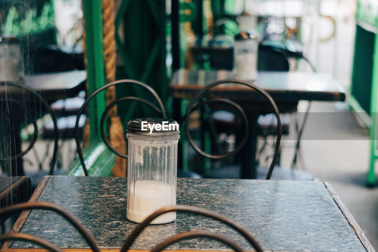 Close-up of empty chairs and table at sidewalk cafe