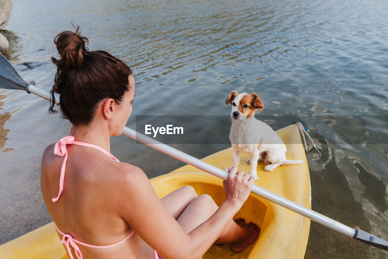 Smiling woman canoeing with dog in lake