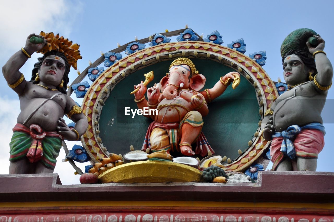 LOW ANGLE VIEW OF STATUE AGAINST TEMPLE